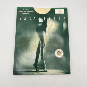 May include: A package of VASSARRETE control top pantyhose in ivory. The packaging is green with the brand name in large white letters. The image on the package shows a woman's legs in the pantyhose.