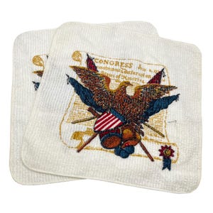 May include: Two white square towels with an embroidered design featuring a brown eagle, American flags, and the text "CONGRESS" on a scroll. The towels have a textured surface.