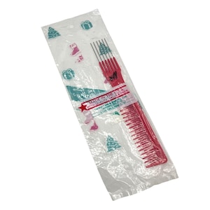 May include: A red comb and pick set in a clear plastic bag with Christmas-themed patterns. The bag has a label that reads "Made in the U.S.A. with Quality, Value & Pride."
