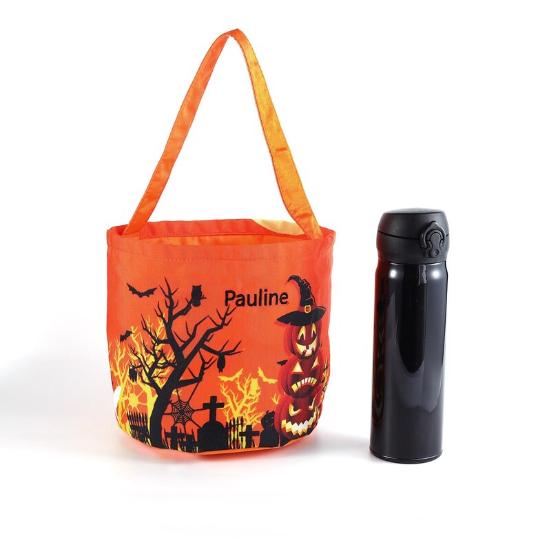 May include: An orange Halloween tote bag featuring a black tree, bats, and jack-o'-lanterns. The bag has an orange handle and the name "Pauline". A black insulated water bottle is next to the bag.