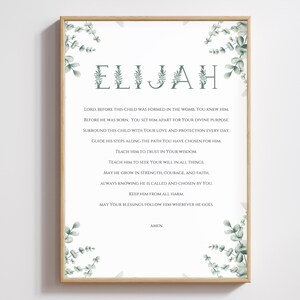 Puede incluir: Un diseño de arte de pared imprimible con un fondo blanco y acentos de follaje verde. El diseño presenta el nombre "ELIJAH" en una fuente decorativa y una oración para el niño. El texto dice: "Señor, antes de que este niño fuera formado en el vientre de su madre, tú lo conocías. Antes de que naciera, tú lo apartaste para tu propósito divino. Rodea a este niño con tu amor y protección todos los días. Guía sus pasos por el camino que has elegido para él. Enséñale a confiar en tu sabiduría. Enséñale a buscar tu voluntad en todas las cosas. Que crezca en fortaleza, coraje y fe, sabiendo siempre que él es llamado y elegido por ti. Protégelo de todo mal. Que tus bendiciones lo sigan dondequiera que vaya. Amén."
