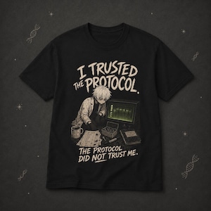 Op de afbeelding: Een zwart t-shirt met korte mouwen en een afbeelding van een persoon in een laboratoriumjas die aan een computer werkt. De tekst luidt I TRUSTED THE PROTOCOL. THE PROTOCOL DID NOT TRUST ME. Het ontwerp bevat een mok, een lijst en een boek.