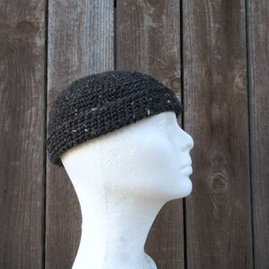 May include: A black crocheted beanie with a slouchy fit. The beanie is made with a textured yarn and has a subtle sheen.