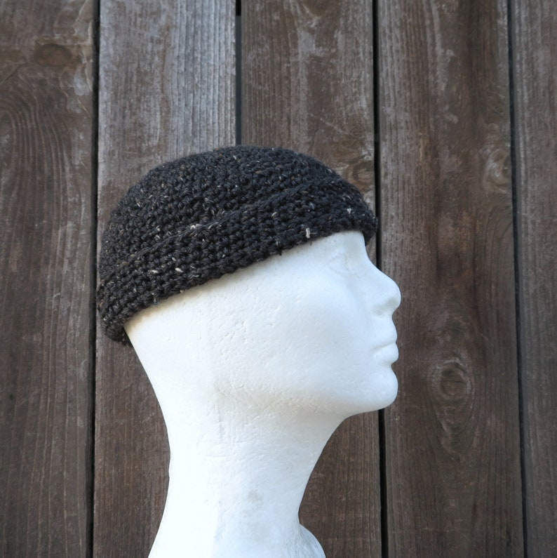 May include: A black crocheted beanie with a slouchy fit. The beanie is made with a textured yarn and has a subtle sheen.