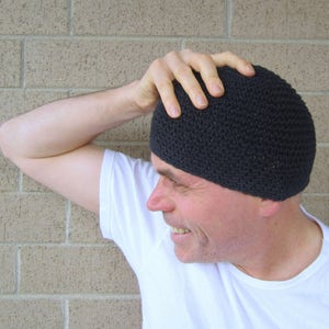 Peut inclure: Un homme portant un bonnet noir en tricot, un t-shirt blanc et une expression pensive.