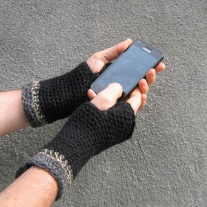 The model is wearing black, crocheted, fingerless gloves with a trim of gray and natural hemp yarn at the top of each glove...they cover his hands but not his fingers and extend to about two inches above his wrists.