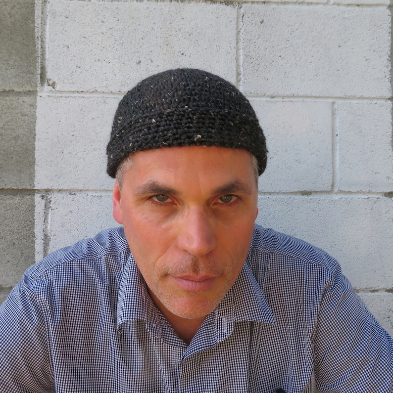 The model is wearing a dark gray tweed, crocheted docker cap with a fold up brim...it fits snugly and extends to just above his ears.