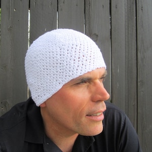 May include: A white crocheted beanie hat. The hat is made with a simple stitch pattern and has a close-fitting style.
