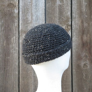May include: A black crocheted beanie with a flecked texture. The beanie has a turned-up brim.