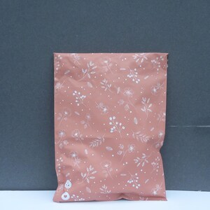 May include: A pink poly mailer with a white floral pattern. The mailer is made of a durable, water-resistant material and is perfect for shipping small items.
