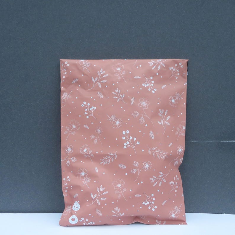 May include: A pink poly mailer with a white floral pattern. The mailer is made of a durable, water-resistant material and is perfect for shipping small items.