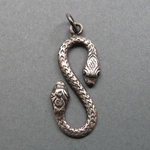May include: A silver snake pendant with two heads, each with detailed scales and a textured surface.