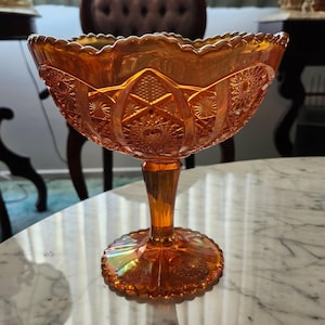 Könnte beinhalten: Eine antike Bonbonschale aus bernsteinfarbenem Glas mit einem gewellten Rand und einem komplizierten geschliffenen Glasdesign. Die Schale steht auf einem Sockel.