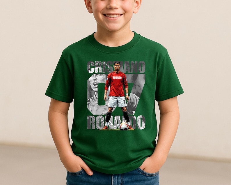 May include: A dark green short-sleeved t-shirt featuring a graphic print of Cristiano Ronaldo in a red jersey and white shorts. The design includes the text CRISTIANO RONALDO and the number 07 in a large font, with a soccer ball at the bottom.