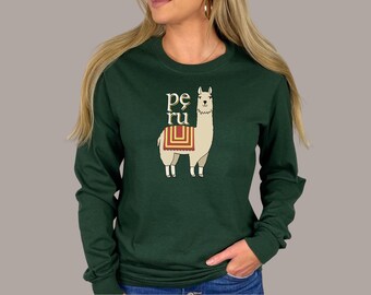 May include: A long-sleeved, dark green shirt featuring a cartoon llama with the word "Peru" above it. The llama has a beige body, white legs, and a colorful blanket. The shirt is made of a soft material.
