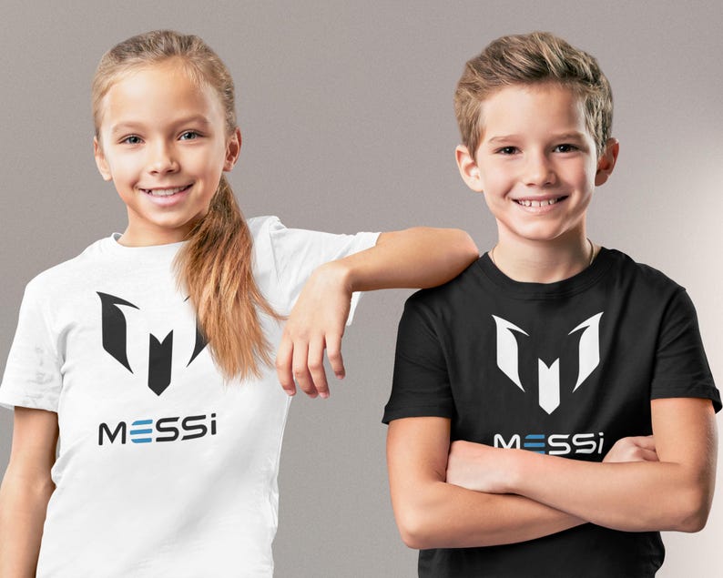 May include: Two children wearing white and black t-shirts with a black and white logo and the word "MESSI" printed on the front.