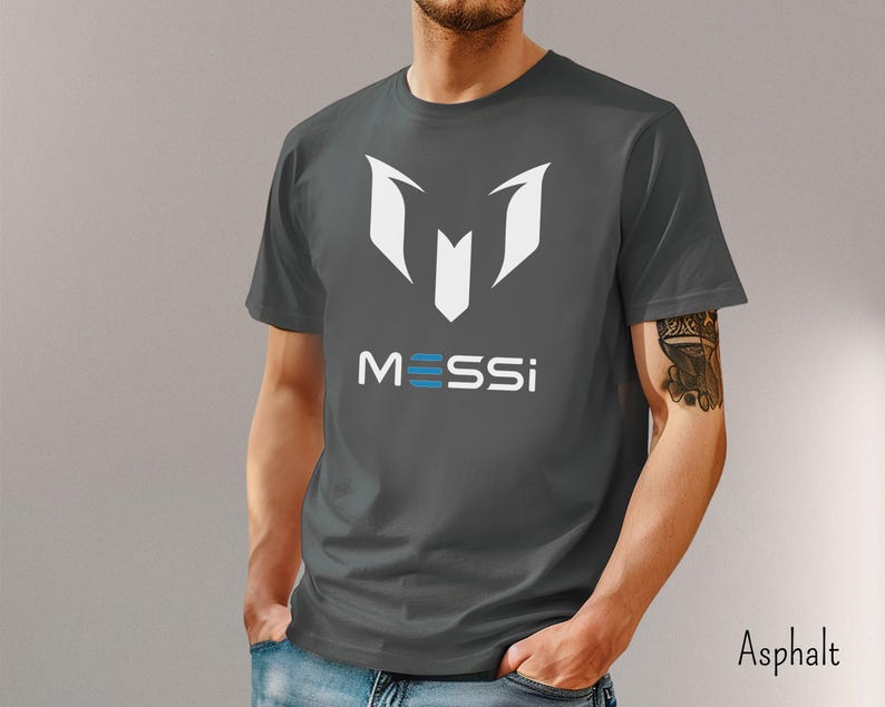 May include: A dark gray t-shirt with a white graphic of the letter "M" and the word "MESSI" in white and blue letters.