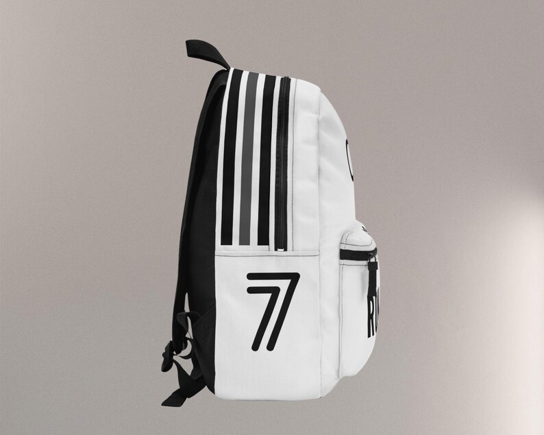 May include: White backpack with black and gray vertical stripes on the side. The number "7" is printed in black on the front. The backpack has a black handle and straps.
