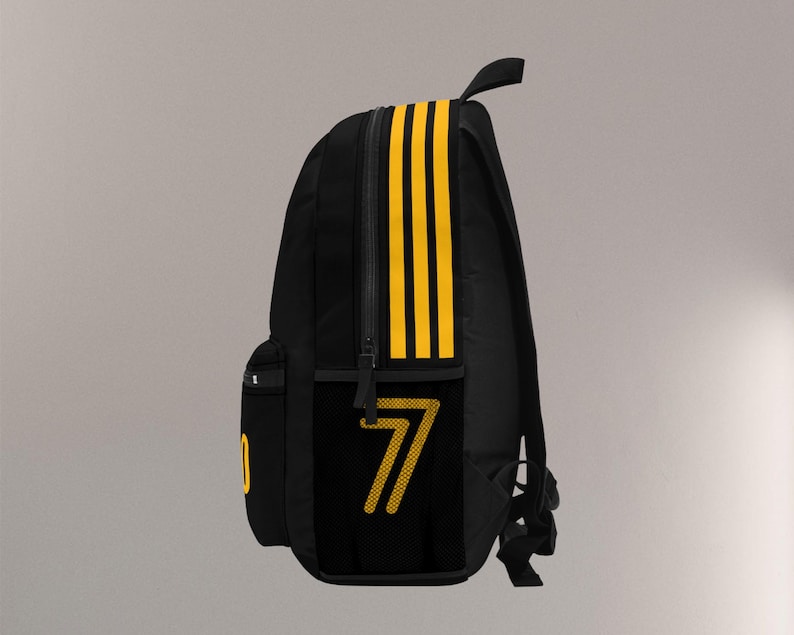 May include: Black backpack with yellow stripes and the number 7. The backpack has a side pocket with the number 7 in yellow. The backpack has a top handle and a front pocket.