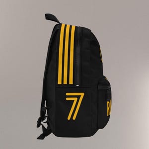 May include: Black backpack with yellow accents. Features three vertical yellow stripes on the side and the number "7" in yellow. Includes a zippered main compartment, a front pocket, and adjustable shoulder straps.