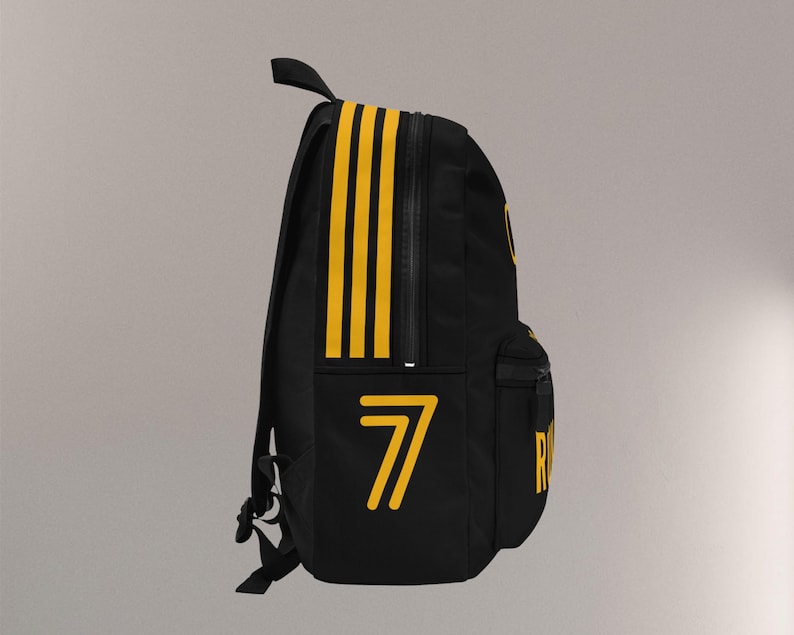 May include: Black backpack with yellow accents. Features three vertical yellow stripes on the side and the number "7" in yellow. Includes a zippered main compartment, a front pocket, and adjustable shoulder straps.