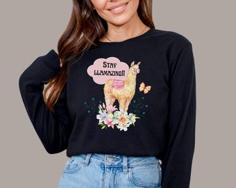 May include: Black long-sleeve shirt with a llama graphic and the text "Stay Llamamazing!" in a pink speech bubble. The llama is wearing a pink saddle and standing in a field of flowers.
