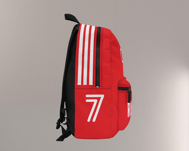 May include: Red backpack with white stripes and the number 7 in white. The backpack has a black back and straps, a top handle, and a front pocket with a black zipper. The word "R" is visible on the side.