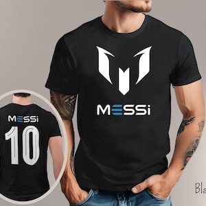 May include: Black t-shirt with a white "M" logo and the word "MESSI" printed below. The back of the shirt has a white number "10" and the word "MESSI" printed above it.