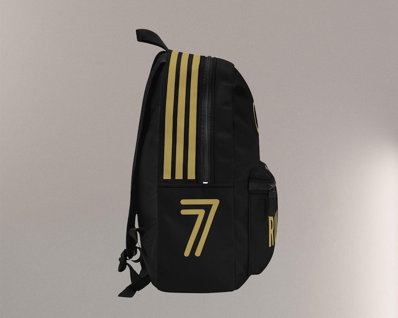 May include: Black backpack with gold accents, including three vertical stripes and the number 7. Features a zippered main compartment, a front pocket, and adjustable straps. The backpack has a top handle for carrying.