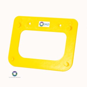 May include: A vibrant yellow rectangular frame with a central aperture and rounded corners. It features small circular studs and holes. A sticker with "JAD" and a colourful logo is visible. The text "JulianAngeloDesigns" is in the bottom left corner.