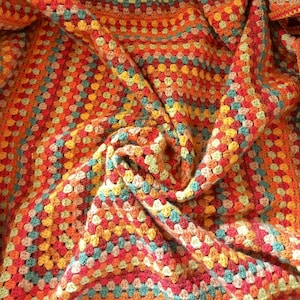 May include: A colorful crocheted blanket with a textured pattern in shades of orange, red, green, and brown.
