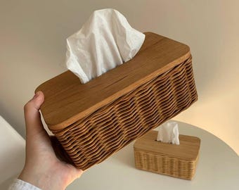 Könnte beinhalten: Ein geflochtener Wicker-Gewebebox-Bezug mit einem Holzdeckel. Der Bezug ist braun und hat ein wellenförmiges Muster. Der Deckel ist aus hellem braunem Holz.