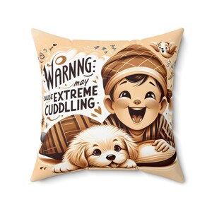 Könnte beinhalten: Ein braunes Kissen mit einer Cartoon-Illustration eines Jungen und eines Welpen. Der Junge trägt einen braunen und weißen Hut und ein gestreiftes Hemd. Der Welpe ist braun und weiß. Der Text auf dem Kissen lautet "WARNING: may cause EXTREME CUDDLING."