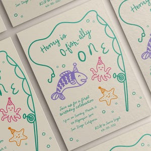 May include: Off-white birthday invitations with a teal border and the text "Henry is o-fish-ally ONE." The invitations feature cartoon fish, octopus, and starfish illustrations in purple, pink, and orange. Includes event details.