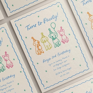 May include: Invitations with a playful design for a dog-themed birthday party. The cards feature colorful line drawings of dogs wearing party hats and the text "Time to Pawty!" in blue script. The cards are on a cream-colored background.