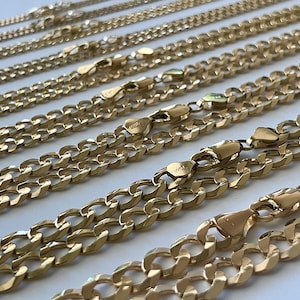May include: A close-up of multiple gold chains of different widths and lengths. The chains are arranged in a staggered pattern, with the widest chain at the bottom and the narrowest chain at the top.