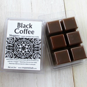 May include: Two clear plastic containers of scented wax melts. One container has a label that reads "Black Coffee Nuggets super scented wax melts." The other container holds six brown, cube-shaped wax melts. The label also includes a black and white design.