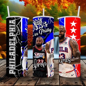 May include: A cylindrical tumbler with a straw featuring a graphic design of LeBron James in Philadelphia 76ers jerseys. The design includes the text PHILADELPHIA, King in Philly, and LeBron James, set against a background of blue and red lightning.