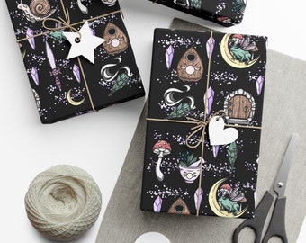 Peut inclure: Papier d'emballage noir et blanc avec un motif répétitif de cristaux, de champignons, un chaudron, une lune croissante, une grenouille, une porte et une planche Ouija. Le papier est enveloppé autour d'une boîte cadeau avec une étiquette en forme de cœur blanche.