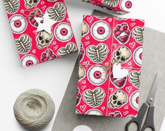May include: Gift-wrapped boxes with a red background and a repeating pattern of skulls, eyeballs, hearts, and rib cages. The gifts are tied with twine and adorned with white heart-shaped tags. A ball of twine and scissors are also visible.