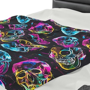 May include: A black fabric with a repeating pattern of colorful neon skulls. The skulls are outlined in yellow and have pink, blue, and green accents. The background is black with white paint splatters.