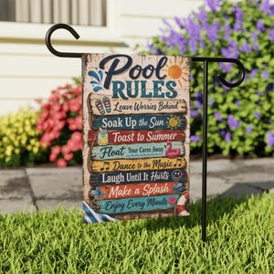 May include: A rectangular garden flag featuring a wood-plank design with the text Pool Rules and various summer-themed icons including flip-flops, a sun, a drink, a flamingo, musical notes, a smiley face, and a life preserver ring on a metal stand.