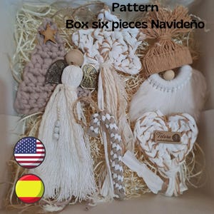 Può includere: Un set di sei ornamenti natalizi all'uncinetto fatti a mano in una scatola. Gli ornamenti includono una stella, un cuore, una canna di zucchero, un angelo, un gnomo e un albero. Gli ornamenti sono realizzati in una gamma di colori beige e bianco.