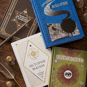 May include: A collection of hardcover books with gold and white lettering and designs. The books are in various colors, including brown, blue, white, and green. A quill, inkwell, and glasses are also present.
