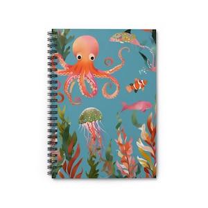 Puede incluir: Una libreta espiral azul con una ilustración de un pulpo, una medusa, un pez payaso y algas marinas. El pulpo es rosa y naranja con una medusa verde y morada. El pez payaso es naranja y blanco con una raya negra. Las algas marinas son verdes y marrones.