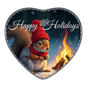 Könnte beinhalten: Herzförmiger Weihnachtsschmuck mit einem Eichhörnchen, das eine rote Mütze und einen Schal trägt, und dem Text "Happy Holidays". Das Eichhörnchen befindet sich in einer verschneiten Szene mit einem Lagerfeuer. Der Schmuck hat einen genähten Rand und ein kleines Loch zum Aufhängen.