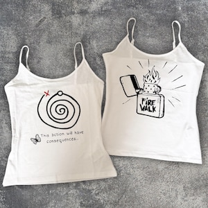 Puede incluir: Dos camisetas sin mangas blancas con diseños gráficos negros. Una presenta una espiral con una X roja y el texto "This action will have consequences..." y una mariposa. La otra tiene un encendedor con el texto "Fire Walk".