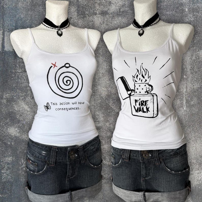 May include: Two white tank tops with graphic designs. One features a spiral with text "This action will have consequences." The other displays a lighter with flames and the words "Fire Walk." Both are paired with denim shorts.