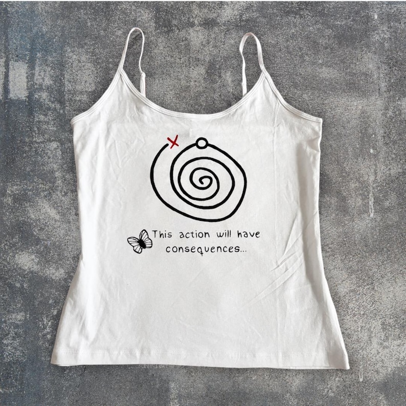 May include: White camisole top with spaghetti straps. The top features a black spiral design with a red X and the text "This action will have consequences..." along with a butterfly graphic. The top is made of a soft, lightweight fabric.