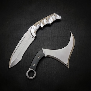 Puede incluir: Dos cuchillos plateados con mangos negros. Un cuchillo tiene una hoja curva y el otro tiene una hoja recta.